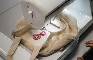 Eine Stickmaschine stickt die programmierte Stickerei auf einen Stoffbeutel